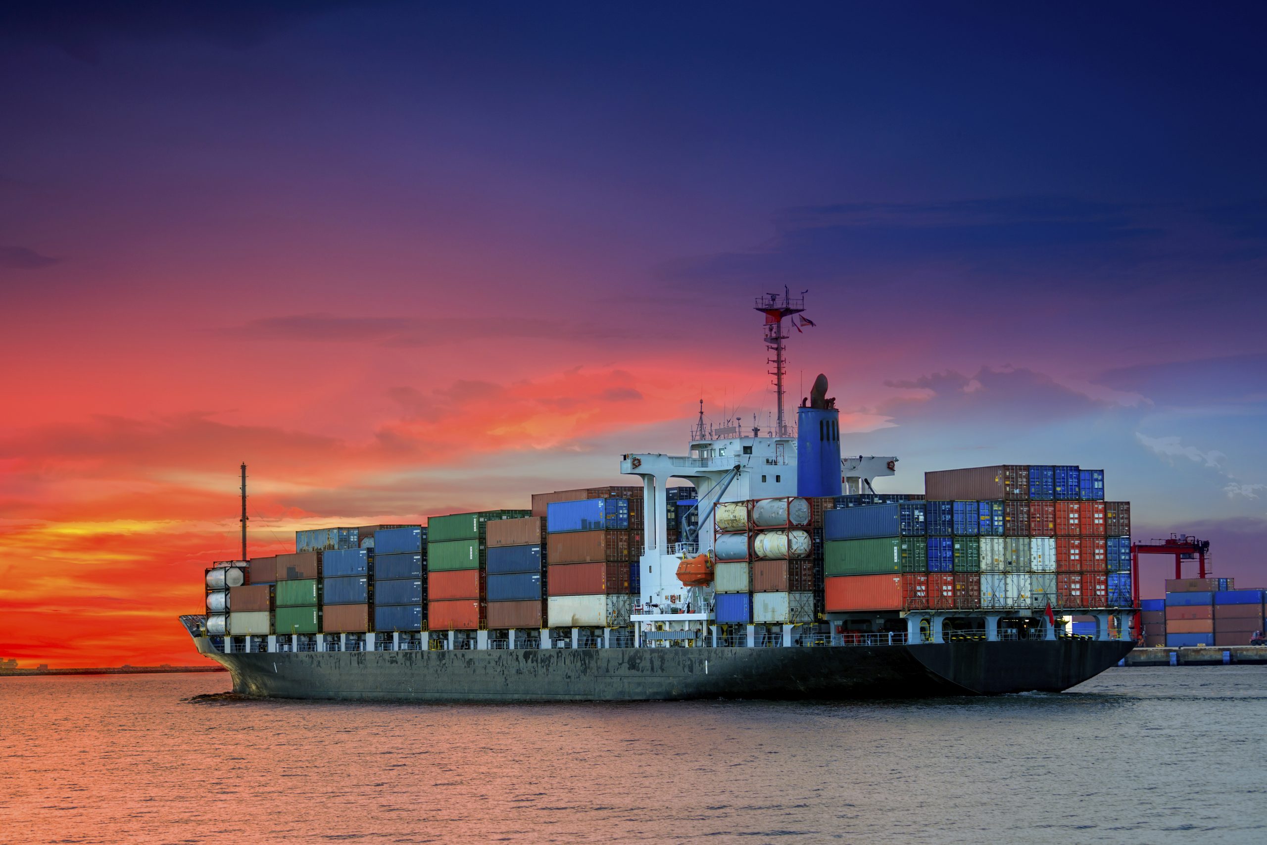 cargo container ship at mediterranean coast in sunset